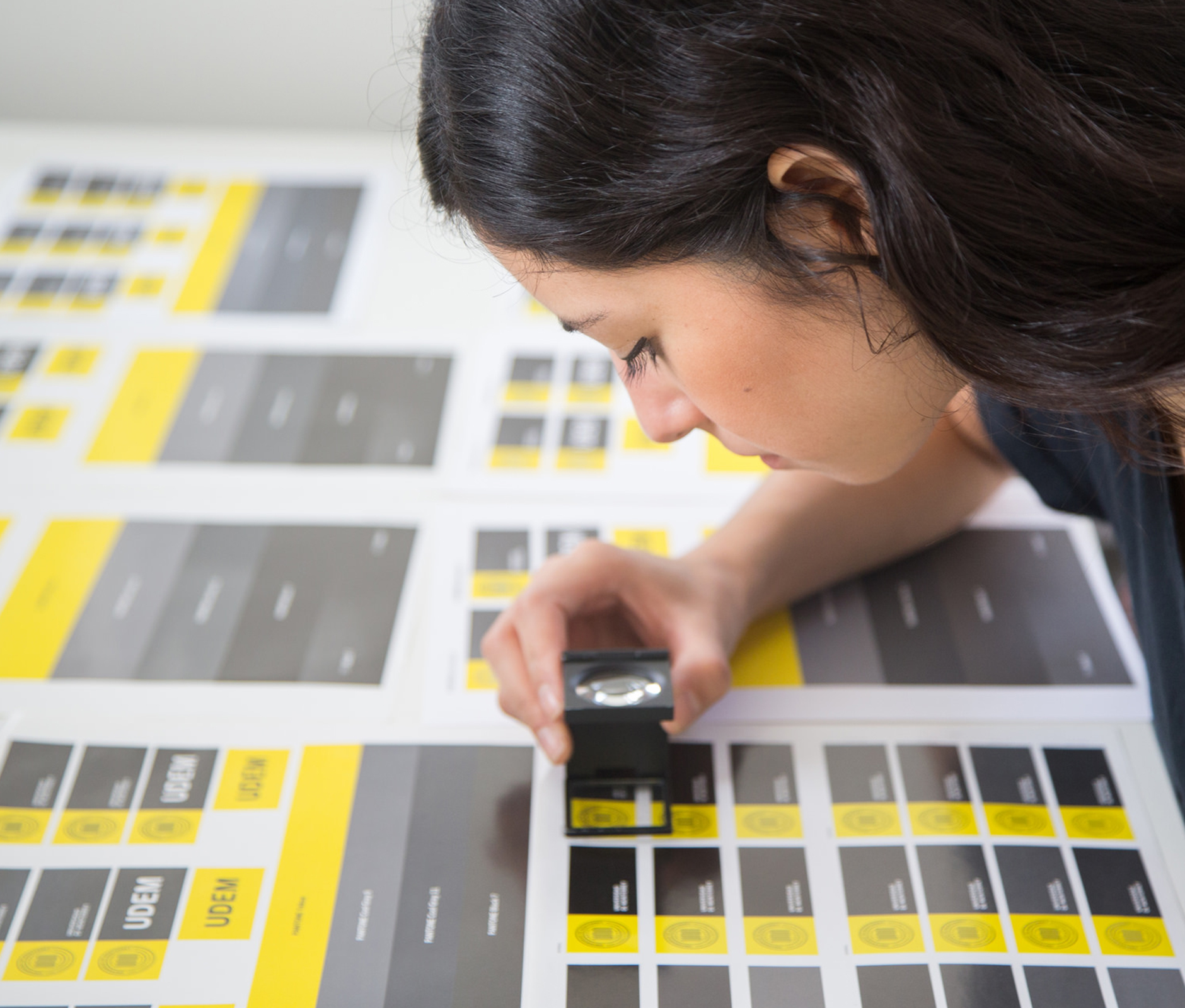 Design student revising work with magnifying glass