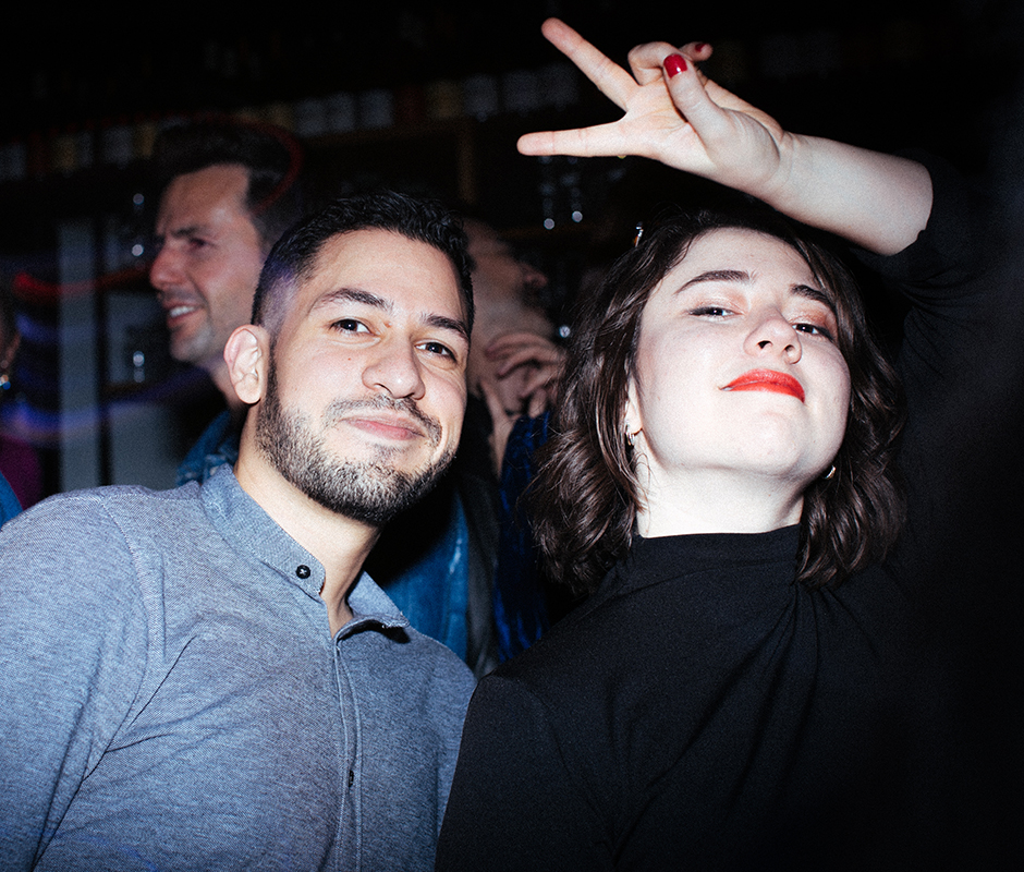 Woman throwing peace sign in the air photographed with friend
