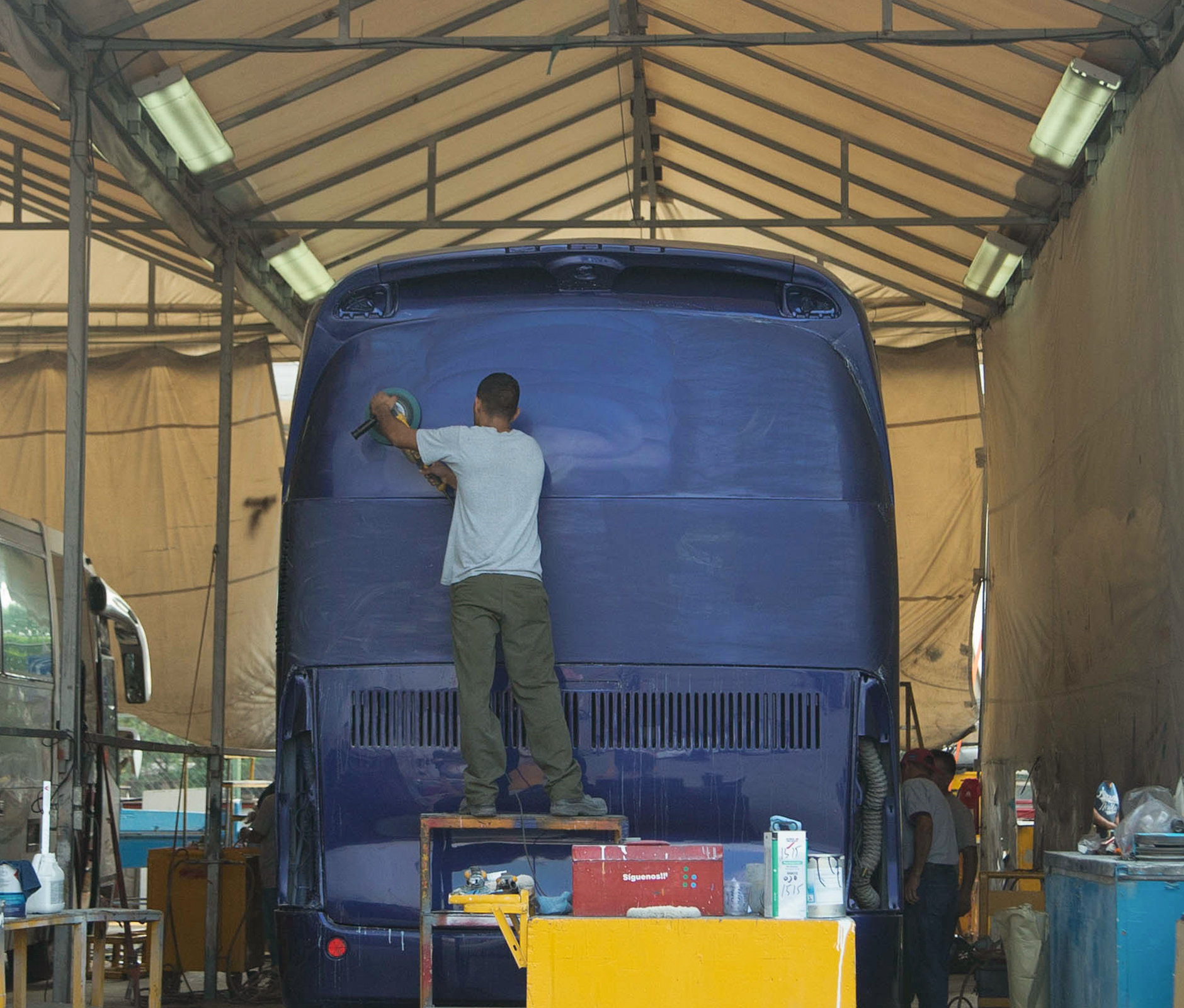 Man cleaning road bus in workshop garage