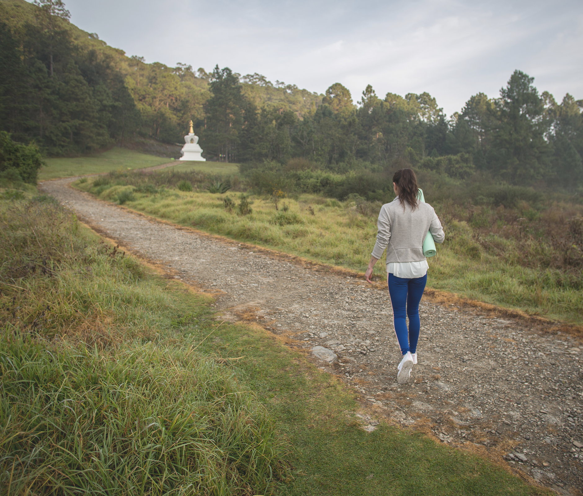 Woman strolling in the woods with yoga mat