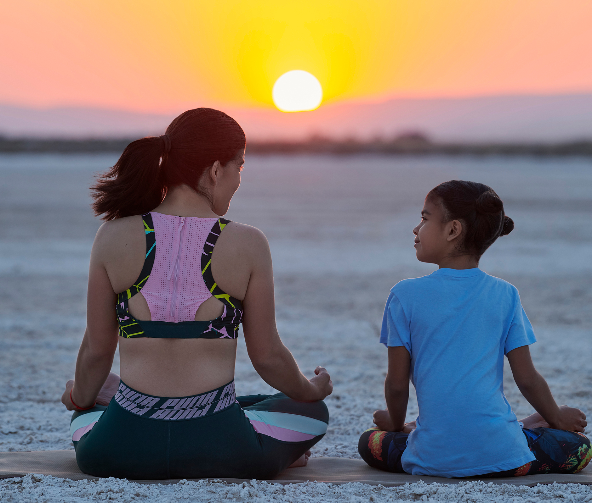 Mother and daughter meditating together in the desert