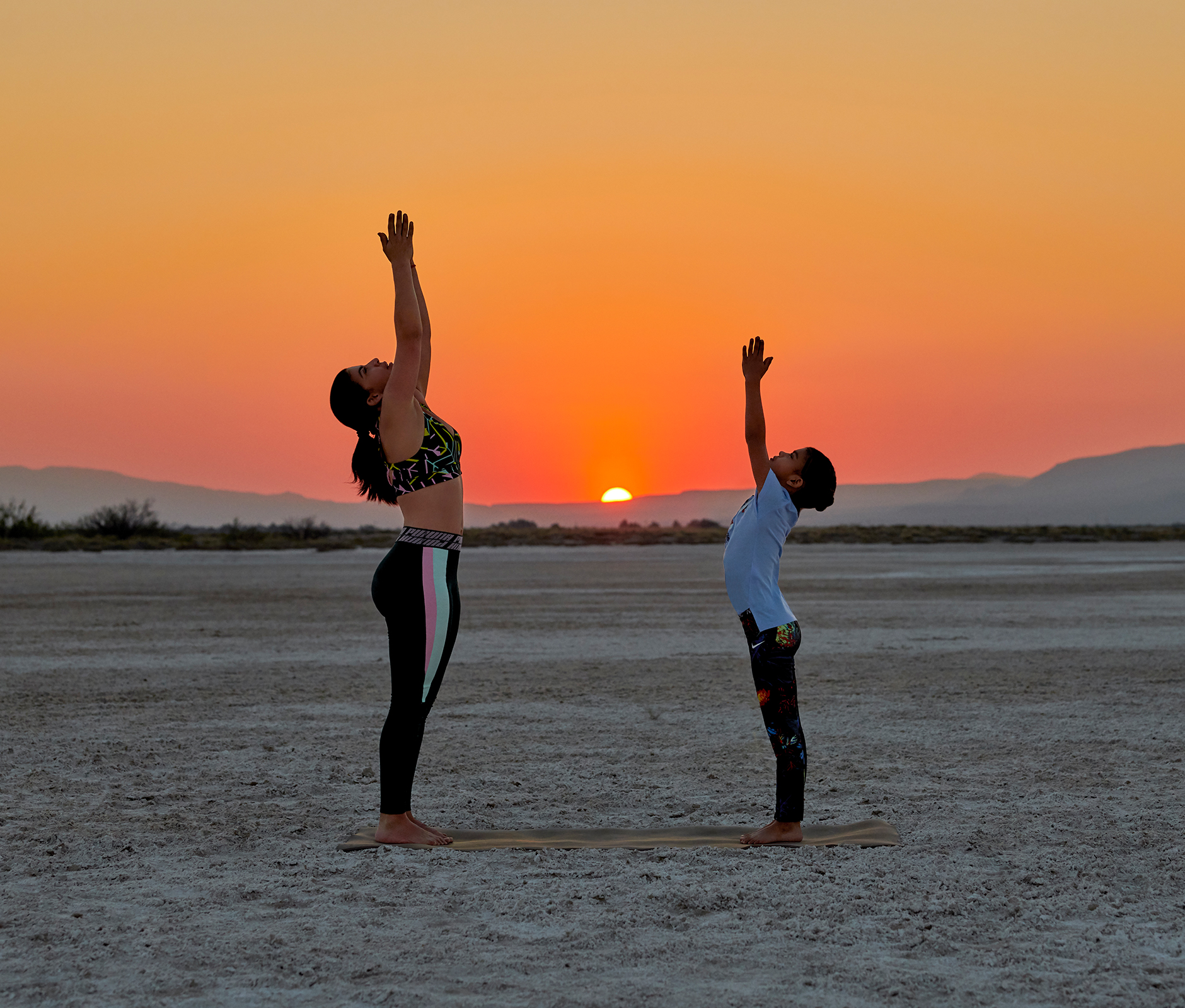 Mother and son practising yoga in the desert at sunset 