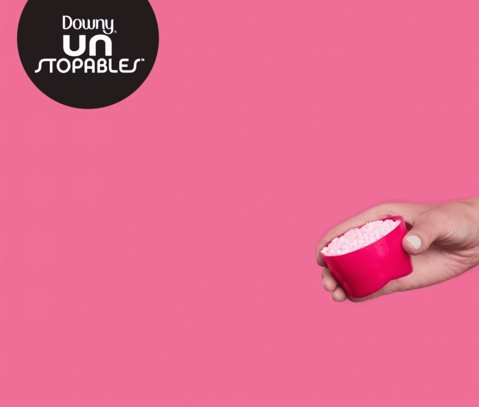 Hand pouring Downy detergent on a pink cup