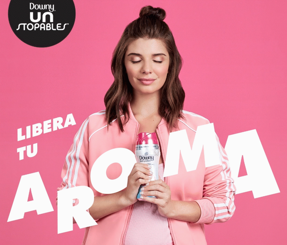 Woman inhaling while holding a bottle of Downy Unstoppable