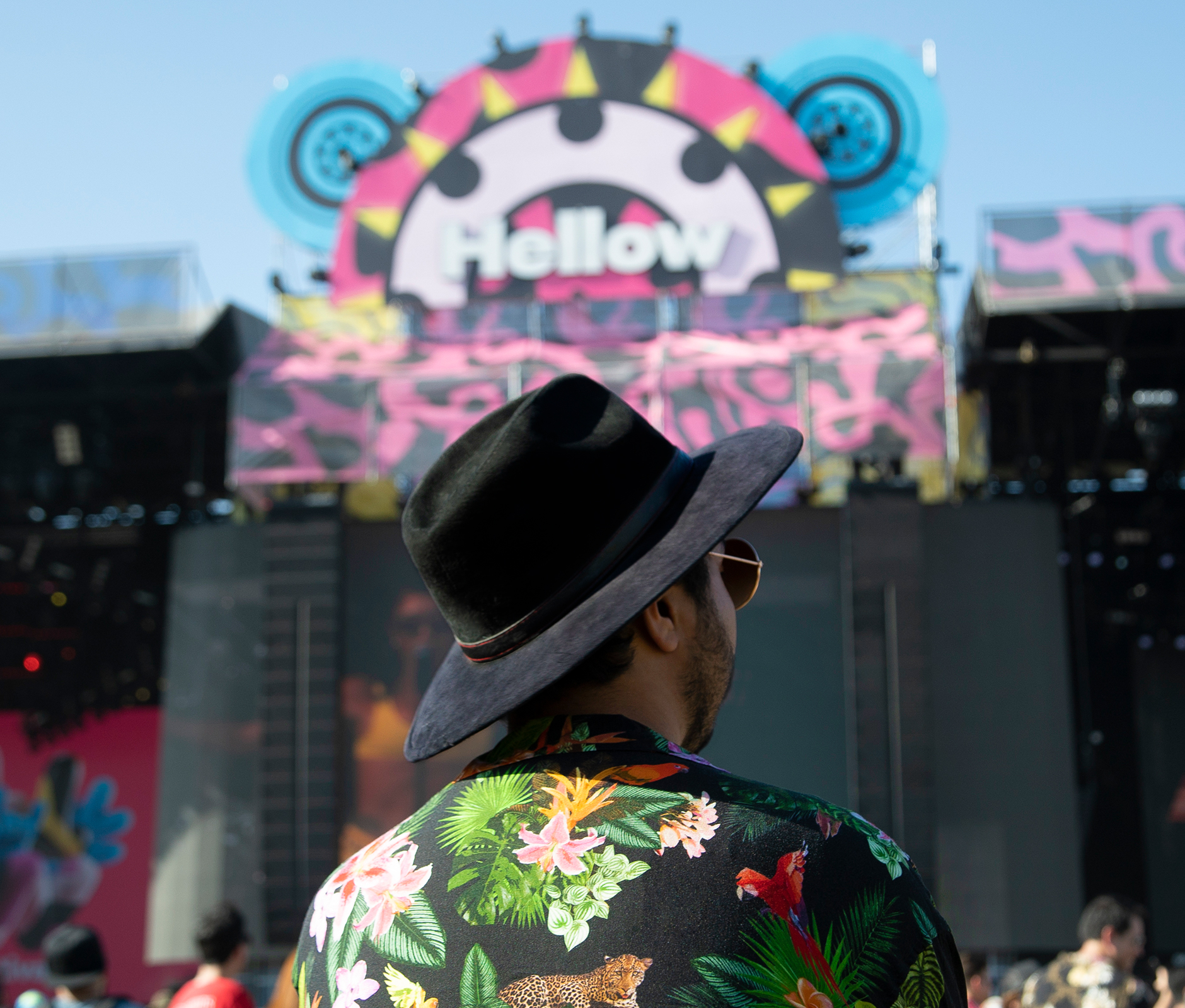Man wearing hawaiian shirt and black hat standing in front Hellow Festival stage
